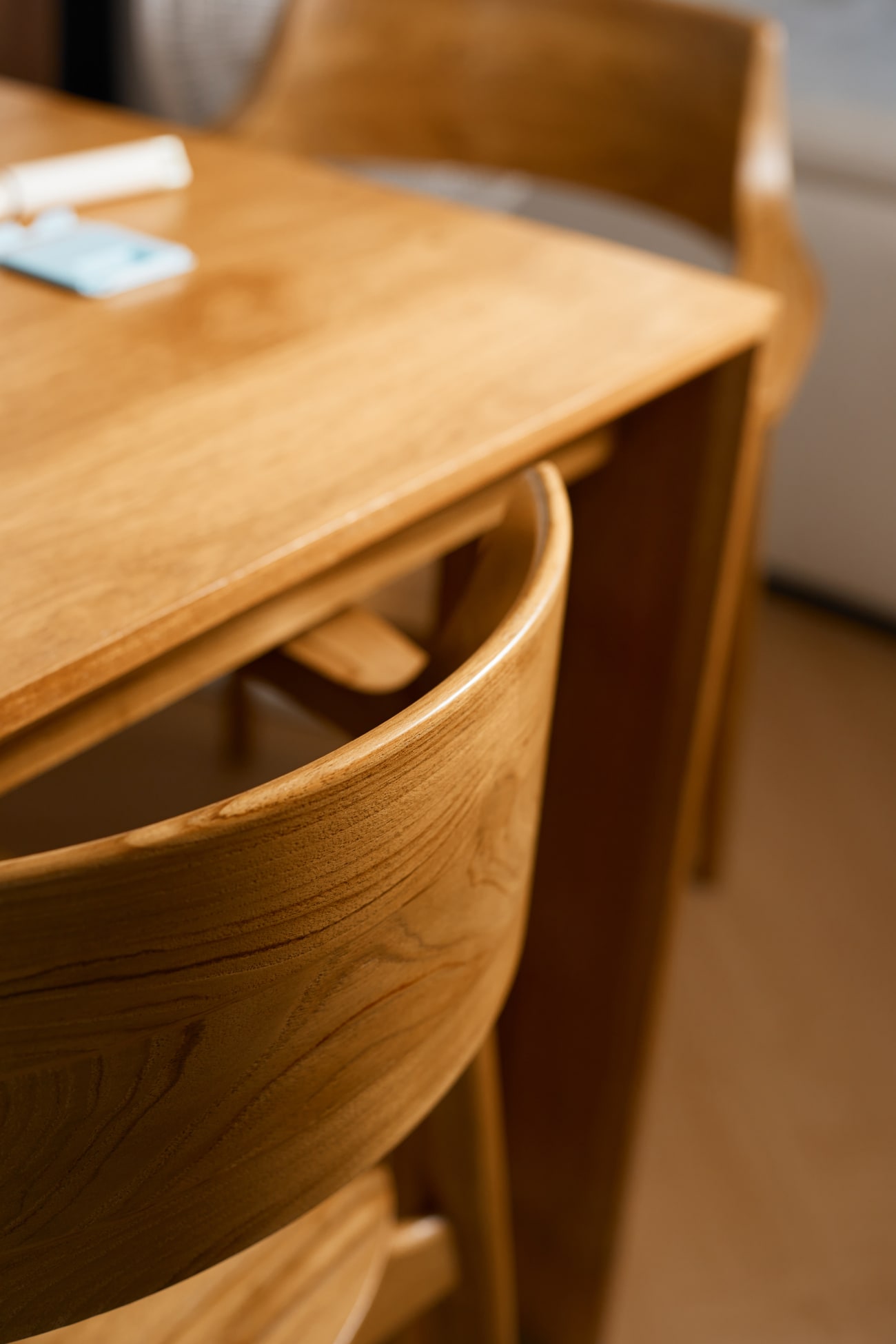 Holztisch mit Stühlen im Vordergrund, Fokus auf der Holzstruktur und der Tischoberfläche.